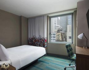 A single bed guest room in the Aloft Manhattan Downtown - Financial District, with TV and workspace desk and chair.