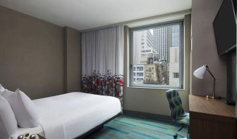 A single bed guest room in the Aloft Manhattan Downtown - Financial District, with TV and workspace desk and chair.