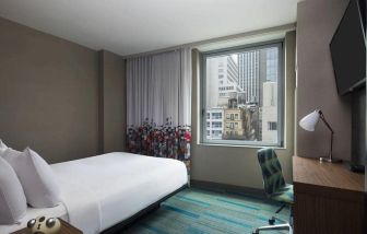 A single bed guest room in the Aloft Manhattan Downtown - Financial District, with TV and workspace desk and chair.