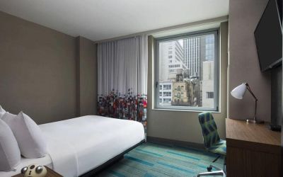 A single bed guest room in the Aloft Manhattan Downtown - Financial District, with TV and workspace desk and chair.