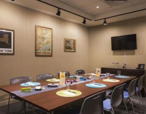 Meeting room with long wooden table, eight chairs, and nearby widescreen TV.