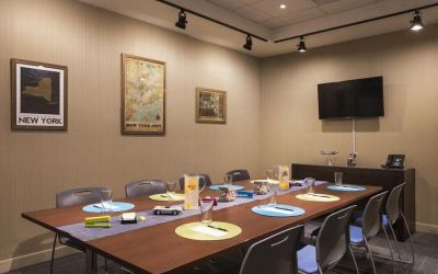 Meeting room with long wooden table, eight chairs, and nearby widescreen TV.