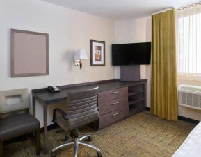 Workspace in a Candlewood Suites Times Square guest room, with desk, chair, TV, and window.