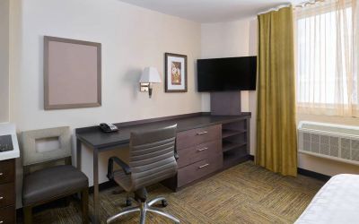Workspace in a Candlewood Suites Times Square guest room, with desk, chair, TV, and window.