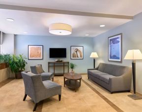 The lounge in the Candlewood Suites Times Square lobby, with comfy chairs, sofa, table, and TV.