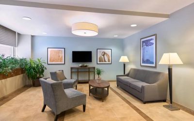 The lounge in the Candlewood Suites Times Square lobby, with comfy chairs, sofa, table, and TV.