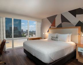 Double bed guest room in The Beeman Hotel, featuring large bed, and city view through the window.