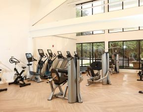 The hotel fitness center is brightly lit and has a broad selection of exercise machines.