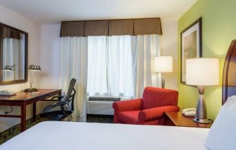 Guest room in Hilton Garden Inn Queens/JFK Airport with armchair and window.