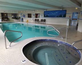 The hotel’s indoor pool has nearby chairs and three foot depth hot tub.