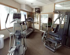 The hotel fitness center has multiple exercise machines and an overhead TV.