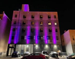 The hotel’s exterior is illuminated with purple lights and offers ample parking.