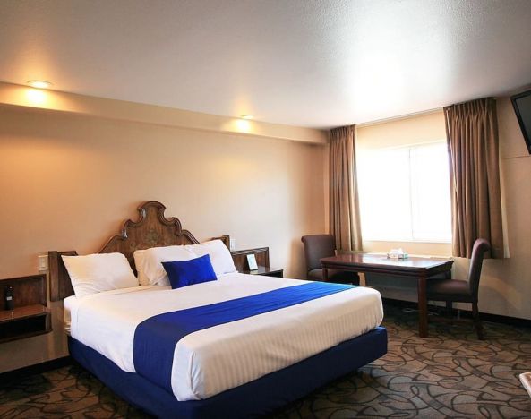 Delux king bed with TV and business desk at Colony Inn Universal Studios.