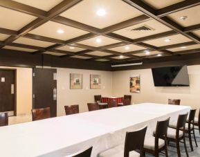 Hotel meeting room, featuring long table, surrounding chairs, and large TV.