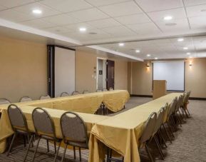 Meeting room in The Staten Island Inn, with three tables arranged in a U-shape, plus lectern and projector screen.