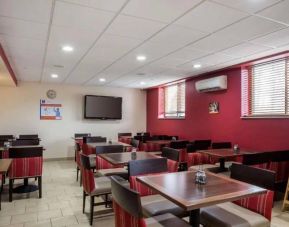 Hotel breakfast area, including hard floor, tables for four, and large TV.