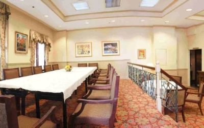 Hotel meeting room, with long table, surrounding chairs, and a large TV on the wall.