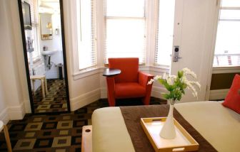 Guest room of The Mosser Hotel, with bed, chair, windows, and ensuite bathroom.