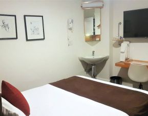 Guest room inside The Mosser Hotel, featuring a workspace desk and chair plus large TV.