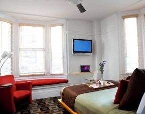 The Mosser Hotel guest room, including TV, chair, bed, and nearby window.