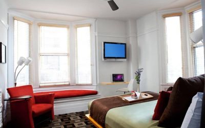 The Mosser Hotel guest room, including TV, chair, bed, and nearby window.