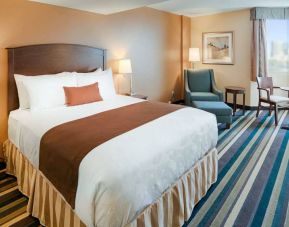 Double bed guest room in Best Western Plus Winnipeg Airport, featuring window, armchair, and foot stool.