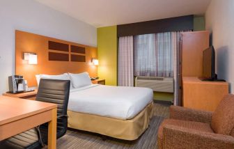 One of Holiday Inn Express Times Square’s guest rooms, with comfy chair, space for working, and window, plus double bed.