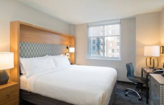 One of Holiday Inn Express Wall Street’s guest rooms, complete with double bed, window, and workspace chair and desk.