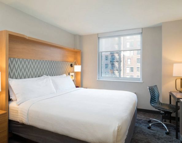 One of Holiday Inn Express Wall Street’s guest rooms, complete with double bed, window, and workspace chair and desk.