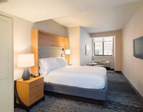 Guest room in the Holiday Inn Express Wall Street, with large television, chairs, and window.