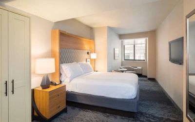 Guest room in the Holiday Inn Express Wall Street, with large television, chairs, and window.