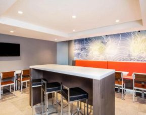 The hotel’s breakfast area, with hard floor, regular chairs and tables, and tall stools.