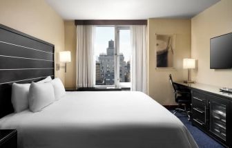 Delux king room with TV and business desk at Hilton New York Fashion District.