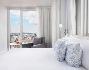 One of the NoMo Soho’s guest rooms, with double bed, chair, and great view of the city.