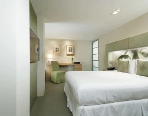 A guest room in the The Shoreham, with large bed, art on the wall, and workspace desk and chair.