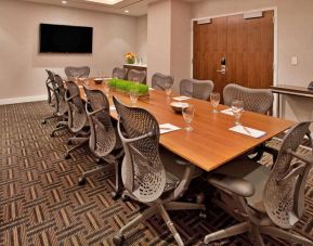 Meeting room with long wooden table and a dozen swivel chairs around it.