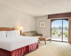 Comfortable king bed with natural light and terrace at Golden Sails Hotel Long Beach.