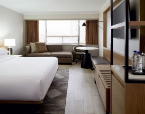 King bed with TV and lounge area at Sheraton Montreal Airport Hotel.