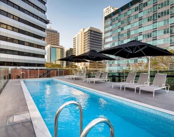 Stunning outdoor pool with seating area at Vibe Hotel North Sydney.