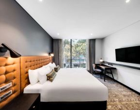 Comfortable king bed with TV and business desk at Vibe Hotel North Sydney.