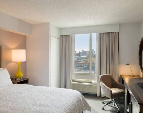 King bedroom with TV, desk, and natural light at Hampton Inn Manhattan Chelsea.