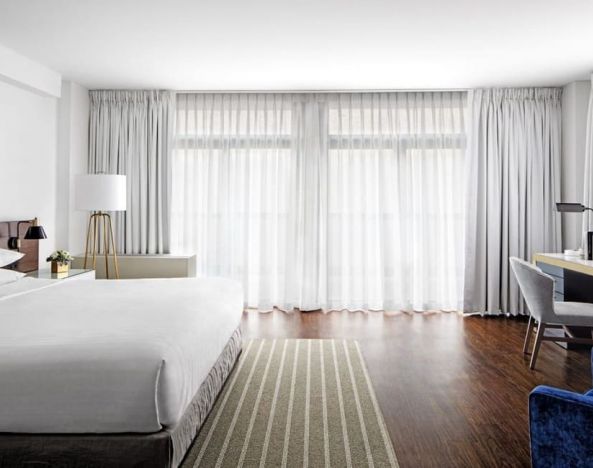 King bedroom with desk, chair, and natural light at St Gregory Hotel.