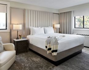 Delux king bed with chair and natural light at Capitol Hill Hotel.