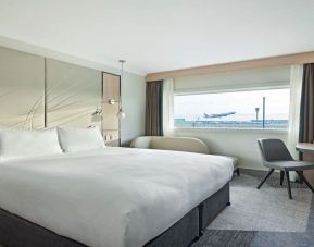 King bedroom with work desk and natural light at Hyatt Place London Heathrow Airport.