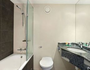 Private guest bathroom with shower and bath at Hyatt Place London Heathrow Airport.