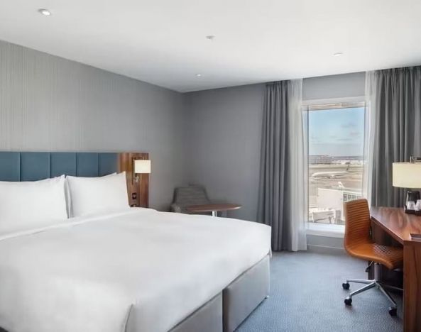 King bed with TV and work station at Hilton Garden Inn London Heathrow Terminals 2 And 3.