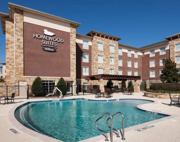 Lovely outdoor pool with seating area at Homewood Suites By Hilton Denton.