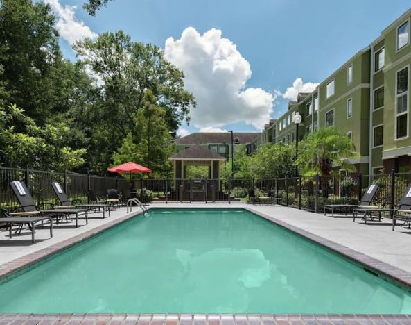 Large outdoor pool with pool chairs at Homewood Suites By Hilton Lafayette-Airport, LA.