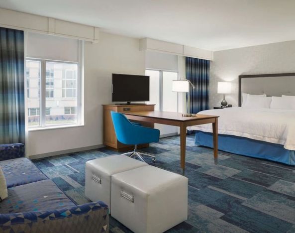 Spacious delux king bed with lounge area at Hampton Inn & Suites Rosemont Chicago O'Hare.