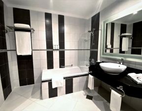 Guest bathroom with shower and bath at Millennium Central Doha.